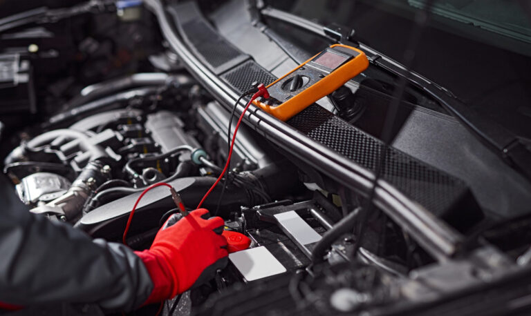 mecanic imeasuring voltage of a vehicle battery with voltmeter